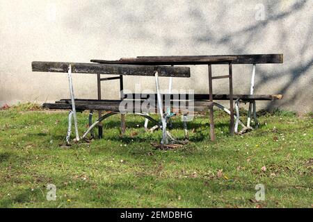Dilapidati vecchio tavolo fatto in casa nel mezzo di due legno panchine del parco pubblico con telaio di supporto in metallo rotto arrugginito e. legno rotto Foto Stock