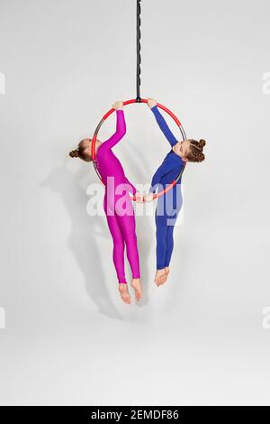 due bambine mostrano una performance acrobatica su un cerchio aereo. acrobata aerea Foto Stock