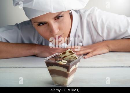 La giovane pasticciera italiana controlla tiramisù, un dolce tipico della pasticceria siciliana focalizzato sulla torta Foto Stock
