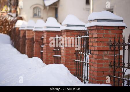 Recinzione antica con cime appuntite in ghisa e colonne in mattoni rossi Foto Stock