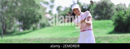 Donna golfer con golf club in mano e palla volante dopo aver colpito Foto Stock