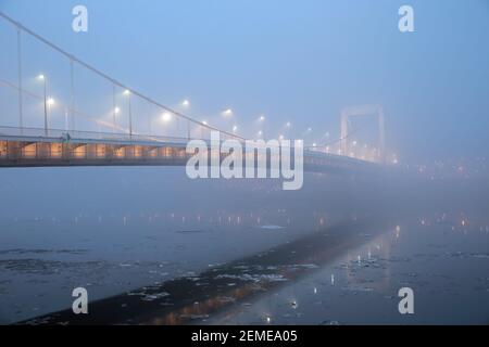 Elizabeth Bridge in misteriosa nebbia sul ghiacciato Danubio a Budapest, Ungheria; foto a colori Foto Stock