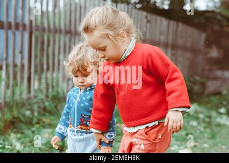 sorella e fratello camminano per la strada in un piccolo villaggio tra le case Foto Stock