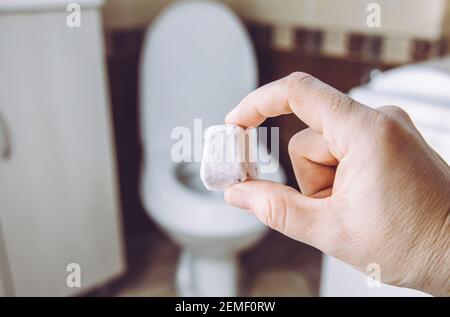 Bomba fizzie da toilette fai-da-te per la pulizia della ciotola della toilette domestica. Fuoco selettivo sulla mano della donna, tenendo la pastiglia di pulizia naturale fatta in casa. Ecocompatibile. Foto Stock