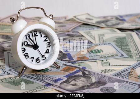 Orologio sullo sfondo di un pacchetto di dollari sulla tavola primo piano, cento dollari washington, mille - texture, sfondo Foto Stock