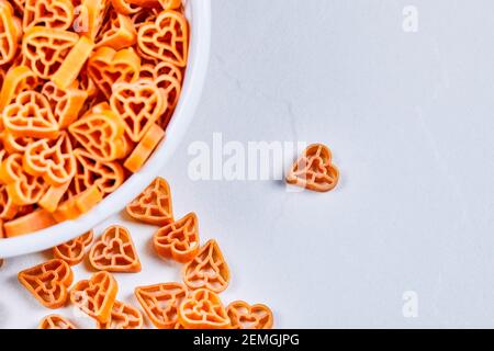 Pasta cruda a forma di cuore nell'angolo di sfondo bianco Foto Stock