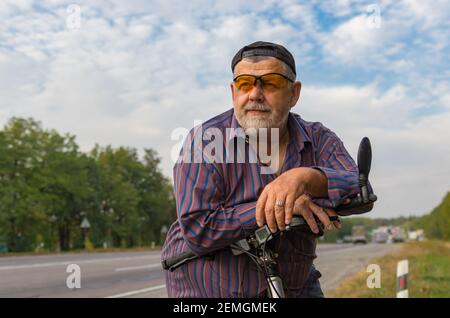 Ritratto esterno dell'uomo anziano caucasico bearded che si sta preparando a. fai un giro in bicicletta Foto Stock