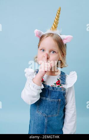 Ragazza carina in testa unicorn band su sfondo blu Foto Stock