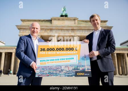 25 febbraio 2021, Berlino: Kai Wegner (l), presidente di Stato della CDU-Berlino, e Stefan Evers, segretario generale della CDU-Berlino, stanno con un cartello di fronte alla porta di Brandeburgo durante una sessione fotografica a seguito di una conferenza stampa della CDU di Berlino sulla petizione per un referendum "espropriato Deutsche Wohnen & Co". Il CDU di Berlino critica la socializzazione degli appartamenti delle società di alloggi privati, come previsto dalla petizione per un referendum. Foto: Christoph Soeder/dpa Foto Stock