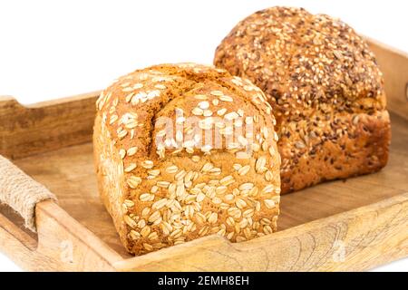 Grappoli di pane integrale con semi e avena su vassoio di legno su sfondo bianco. Foto Stock