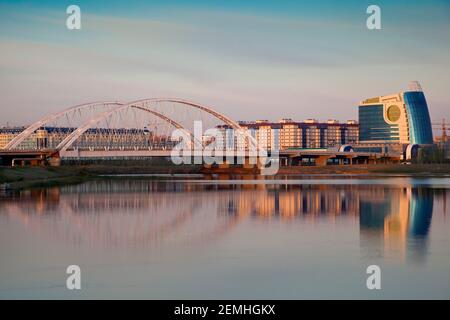 Kazakhstan, Astana, Vista del Fiume Ishim e dello skyline della citta', guardando verso un ponte e un centro affari Foto Stock