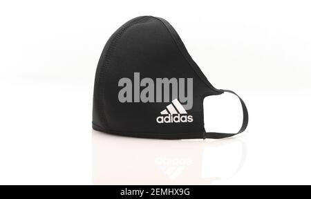 Maschera facciale riutilizzabile Adidas Covid-19 su sfondo bianco con riflessione. Foto Stock
