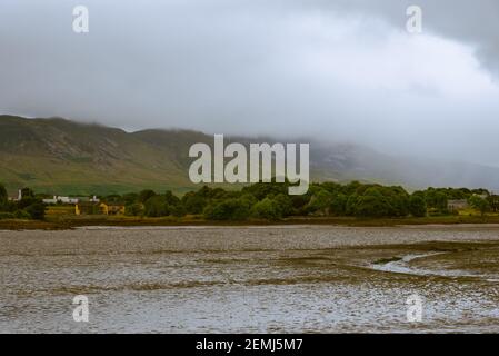 Nebbia rotola giù una montagna verso una riva secca del fiume nella contea di Mayo, in Irlanda di Westport. Foto Stock