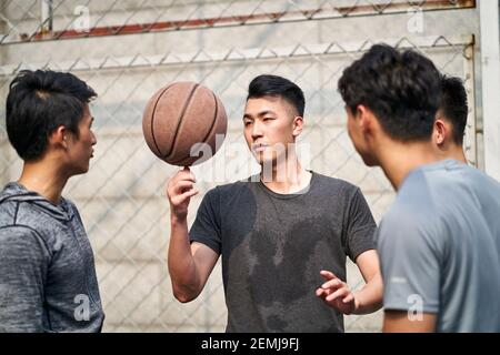 giovani uomini adulti asiatici che si divertono giocando con il basket all'aperto Foto Stock