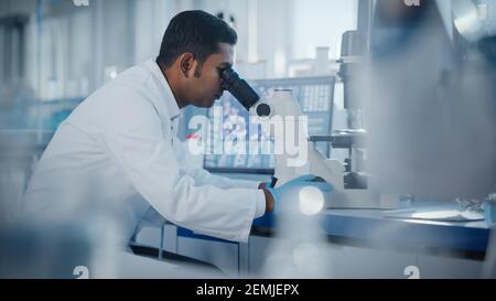 Laboratorio di Ricerca medica: Scienziato maschile che guarda sotto Micrsocope, analizzando i campioni. Laboratorio scientifico avanzato Biotecnologia, Medicina, Microbiologia Foto Stock