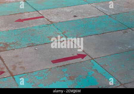 Due frecce direzionali rosse dipinte su una passerella di un bagno (Pesaro, Italia, Europa) Foto Stock