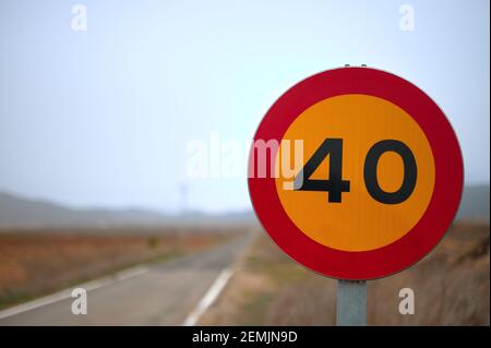 dettaglio di un segnale stradale temporaneo che vieta il traffico oltre i 40 anni km/h con una strada sullo sfondo Foto Stock