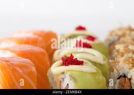Panini di sushi con avocado e caviale di tobiko e panini di philadelphia. Macro. La foto può essere utilizzata come sfondo completo. Foto Stock