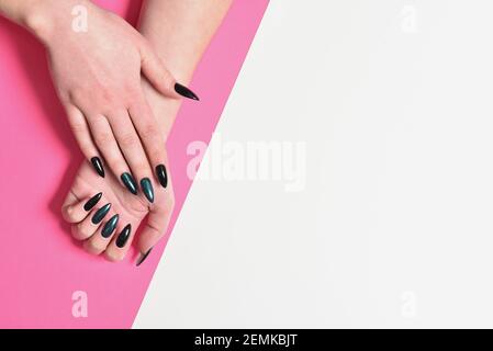 Mani femminili con nuova manicure scura su rosa e bianco sfondo Foto Stock