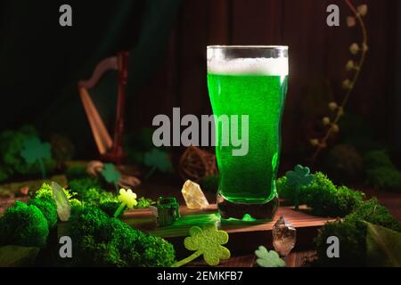 San Patrizio's Day birra verde pinta su sfondo di legno, con foglie di shamrock, arpa. Festa del pub Patrick Day, festeggiando. Primo piano con un bicchiere di birra verde Foto Stock
