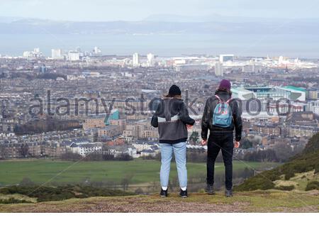 Edimburgo, Scozia, Regno Unito. 25 Febbraio 2021. Le persone che si godono il sole e all'aperto in Holyrood Park. Vista verso nord sull'estuario Forth dalle pendici dell'Arthurs Seat. Credit: Craig Brown/Alamy Live News Foto Stock