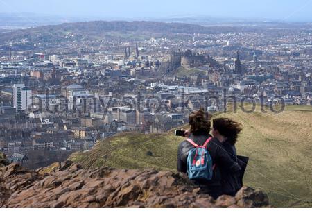 Edimburgo, Scozia, Regno Unito. 25 Febbraio 2021. Le persone che si godono il sole e all'aperto in Holyrood Park. Dalla cima di Arthurs si siede con una vista del Castello di Edimburgo. Credit: Craig Brown/Alamy Live News Foto Stock