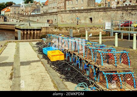 Scatole di plastica colorate su corda e pentole di aragosta ben sistemate Riposa sul pavimento del molo di Berwick Upon Tweed delimitato dalle vecchie mura difensive Foto Stock