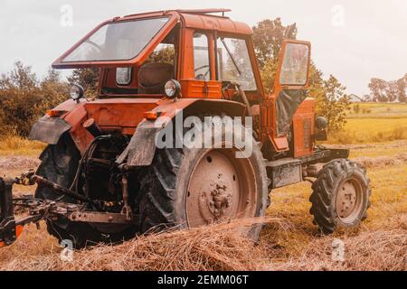 Vecchio trattore rosso nel campo durante la stagione di fieno, premendo fieno sulle balle, mietitura foraggio.2021 Foto Stock