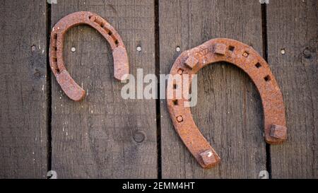 Vecchio ferro di cavallo arrugginito sullo sfondo rustico della parete di legno. Foto Stock