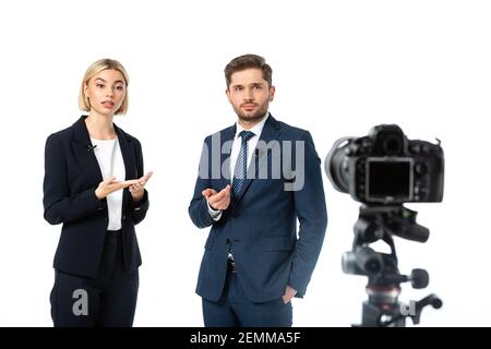 due ancore di notizie che lavorano vicino alla fotocamera digitale su sfocato primo piano isolato su bianco Foto Stock