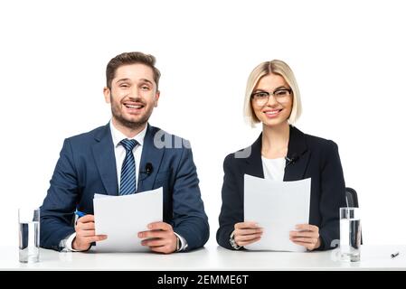 i presentatori di notizie sorridono alla macchina fotografica mentre tengono i documenti sul posto di lavoro isolato su bianco Foto Stock