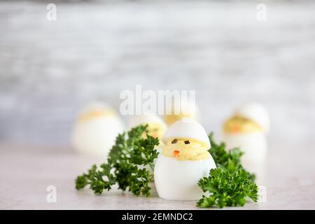 Uova deviled per Pasqua decorate come pulcini carino cova da uova con becco di carota e occhi di alghe. Profondità di campo estremamente bassa con sfocatura Foto Stock