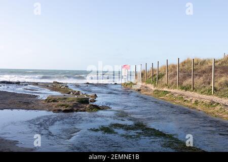 Porthtowan, Cornovaglia, 25 febbraio 2021, River Kennall scorre nel mare a Porthtowan in Cornovaglia, mentre le persone camminavano lungo la spiaggia facendo il loro esercizio quotidiano durante Lockdown. La temperatura era 9C, la previsione è di essere soleggiata e una brezza dolce del Nord Ovest presto per il resto del day.Credit: Keith Larby/Alamy Live News Foto Stock