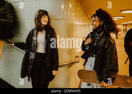 Sorridendo le amiche che si guardano l'un l'altro nella metropolitana illuminata Foto Stock