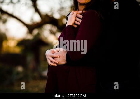 Primo piano delle mani di coppia accanto al Baby Bump Foto Stock