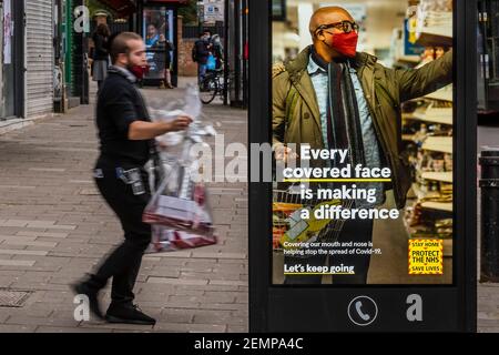 Londra, Regno Unito. 25 Feb 2021. La gente passa i cartelli informativi del Covid del governo mentre si prepara per Purim in Stamford Hill, una delle zone con la più alta incidenza di infezioni di Covid 19 a Londra. Purim è un festival ebraico di 24 ore, che celebra la sopravvivenza degli ebrei minacciati di estinzione in Persia. Comprano i regali di cibo di Mishloach Manos alla famiglia e agli amici. National Lockdown 3 con l'istruzione del governo per tutti di rimanere a casa per salvare la pressione sul NHS. Credit: Guy Bell/Alamy Live News Foto Stock