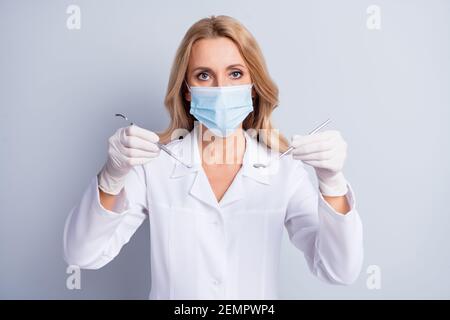 Foto degli strumenti professionali per le mani indossano una cassaforte a freddo maschera medica isolata su sfondo grigio Foto Stock