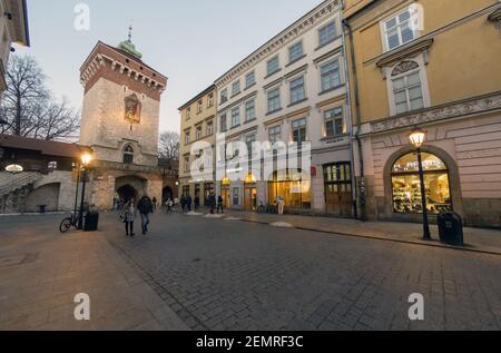 Cracovia, Polonia - 20 febbraio 2021: Inquadratura grandangolare di una strada europea e di persone che passeggiano la sera nella città vecchia di cracovia. Peopl Foto Stock