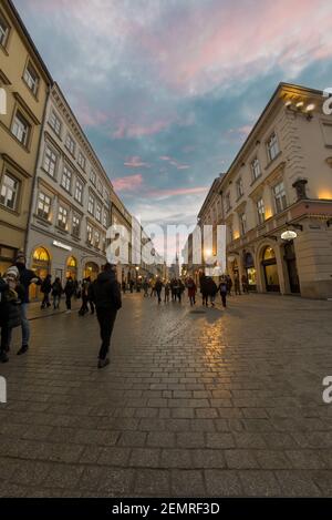 Cracovia, Polonia - 20 febbraio 2021: Immagine verticale di una strada europea e di persone che si prendono una passeggiata durante la sera nella città vecchia di cracovia. Persone Foto Stock