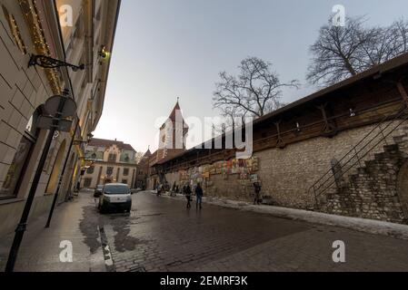 Cracovia, Polonia - 20 febbraio 2021: Inquadratura grandangolare di una strada europea e di persone che passeggiano la sera nella città vecchia di cracovia. Vernice Foto Stock