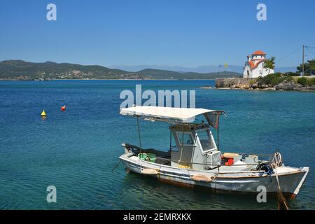 Seascape con una pittoresca barca da pesca greca e vista sulla cappella bizantina di San Pietro e Paolo a Gytheio, Laconia Grecia. Foto Stock