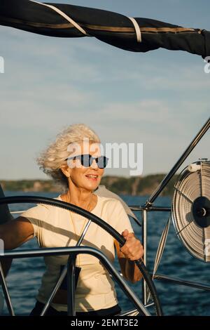 Donna anziana sorridente barca a vela in mare in giornata di sole Foto Stock