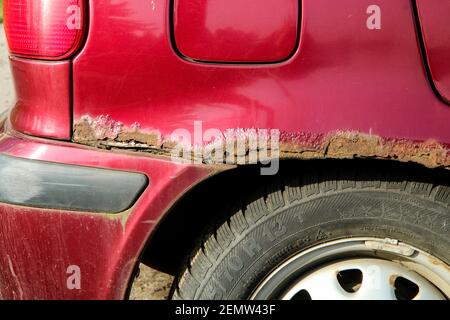 Il dettaglio del parafango sbucciato e arrugginito della vecchia macchina. Immagine della scarsa protezione contro la ruggine. Foto Stock