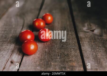 Pomodori ciliegini rossi su sfondo grigio di legno. Foto di alta qualità Foto Stock