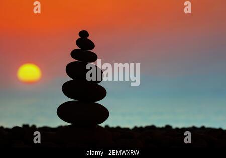 Silhouette torre in pietra sulla spiaggia. Tramonto sullo sfondo sfocato Foto Stock