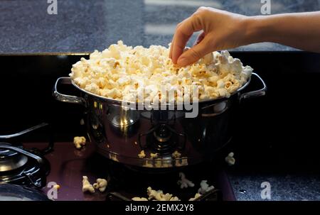 Una teglia in acciaio inox piena di popcorn. Messa a fuoco della foto al centro del popcorn. Sfondo con messa a fuoco morbida. Foto Stock