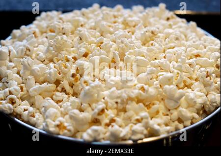 Una teglia in acciaio inox piena di popcorn. Messa a fuoco della foto al centro del popcorn. Sfondo con messa a fuoco morbida. Foto Stock