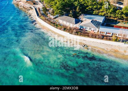Vista aerea sulla costa del mare con edifici vicino all'acqua dell'oceano, splendide acque azzurre, concetto di viaggio estivo. Foto Stock