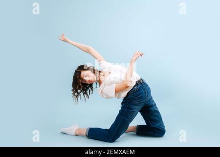 Impressionante ballerina contemporanea si pone di fronte allo sfondo blu dello studio Foto Stock