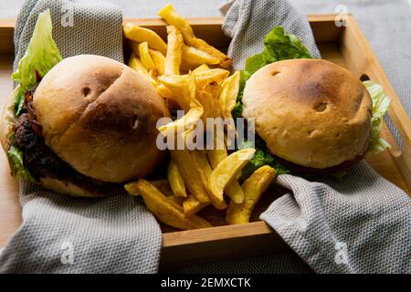 Hamburger di manzo biologico con patatine fritte su tovaglioli di stoffa. Fast food gourmet. Concetto di gastronomia Foto Stock